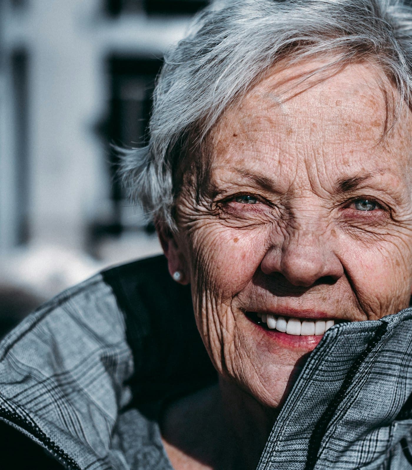 An older woman smiling in warm daylight.